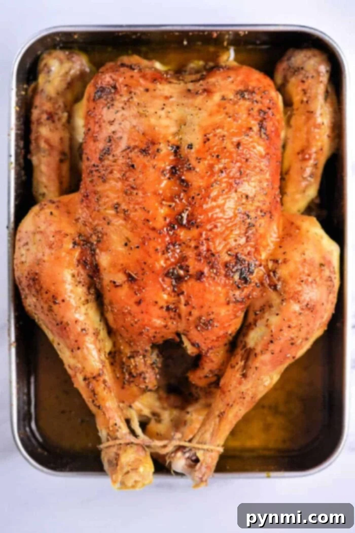 A whole roasted chicken, perfectly golden-brown and crispy, served on a rustic wooden board with a carving knife. The background is blurred, highlighting the delicious chicken. It’s an ideal example of a whole chicken baked in oven at 350 degrees F.