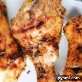 Succulent Grilled Chicken Drumsticks 5 Close-up of grilled, seasoned chicken drumsticks on a white plate.