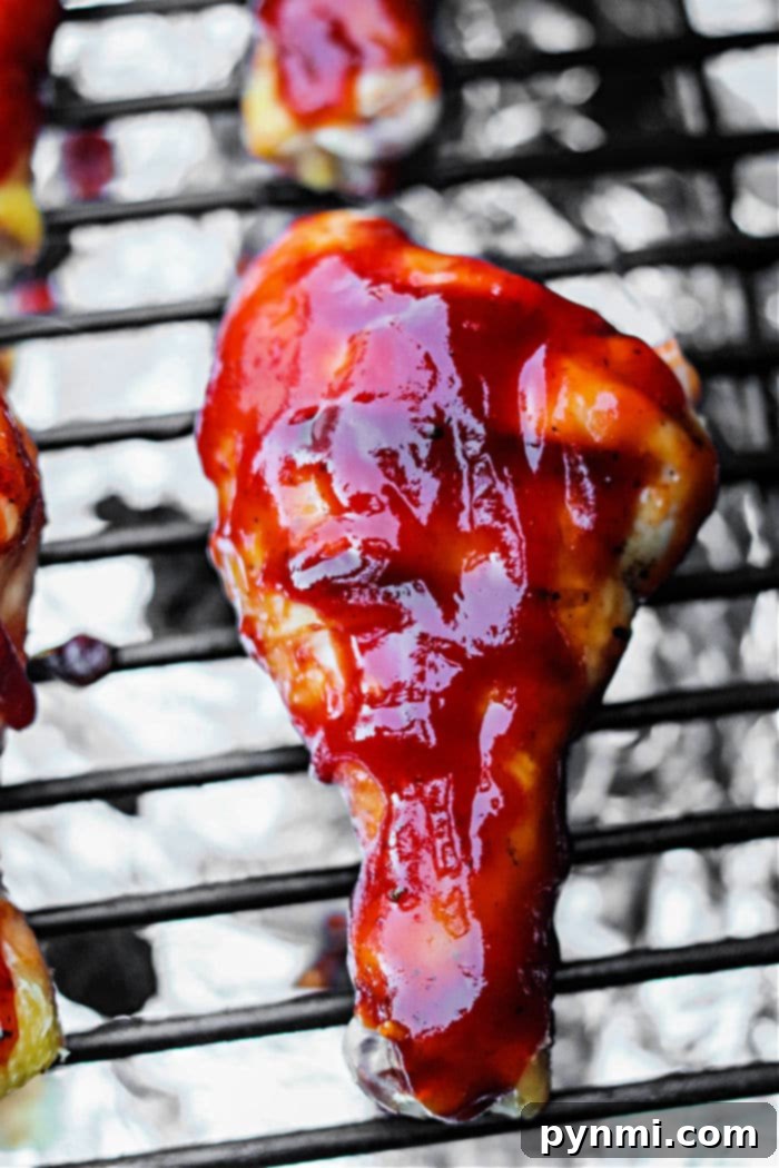 Smoked Chicken Drumsticks, perfectly golden brown and basted with BBQ sauce, resting on a wooden cutting board after being removed from the Traeger grill.