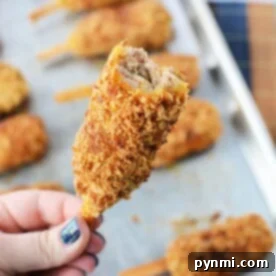 A hand holds a breaded, fried mock chicken with a bite taken, revealing the savory interior reminiscent of mock chicken legs.
