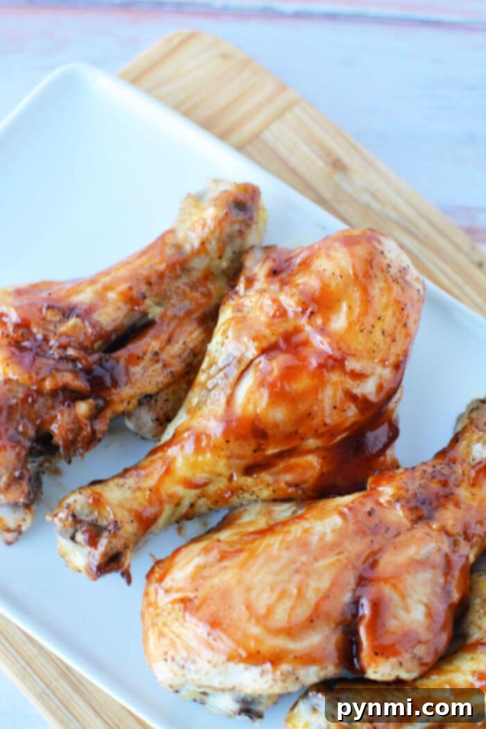 Oven Baked Butterflied Chicken Legs, golden brown and glazed with barbecue sauce, meticulously arranged on a serving platter with fresh herbs for garnish, ready to be enjoyed.