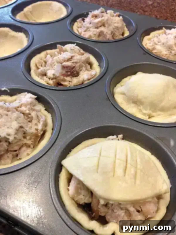 Close-up of chicken pot pie with puff pastry baked in a muffin tin, showing the golden crust and savory filling.