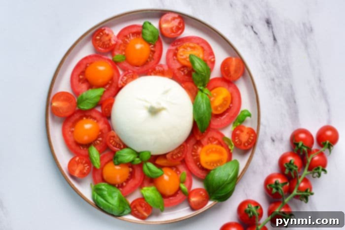 A bowl of Burrata Caprese pasta with cherry tomatoes, basil, and melted burrata cheese.