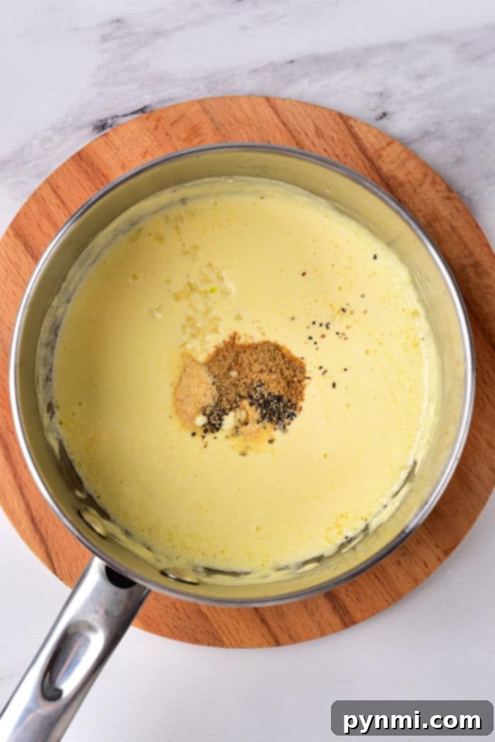 Dairy Free Alfredo Sauce, creamy and white, in a pot with a wooden spoon, ready to be served.