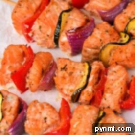 Grilled Salmon Kabobs with zucchini, red pepper, and red onion on parchment paper.