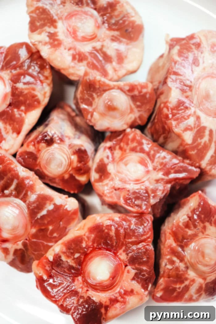Oxtails generously seasoned with herbs and spices, ready for smoking.