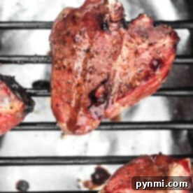 Grilled marinated lamb chops on a barbecue grill with a glossy, browned surface showcasing expert cooking technique.