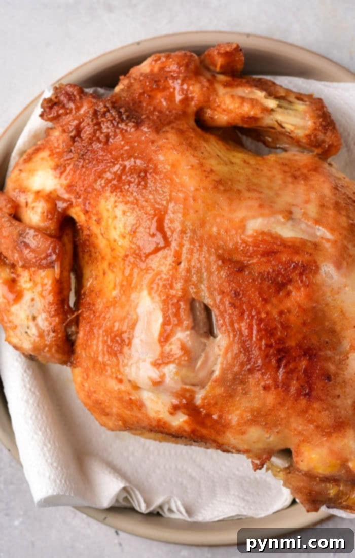 Crispy Whole Fried Chicken Feast 6 A roasted whole chicken with crispy, golden-brown skin rests on a paper towel-lined plate, echoing the mouthwatering allure of a whole fried chicken.
