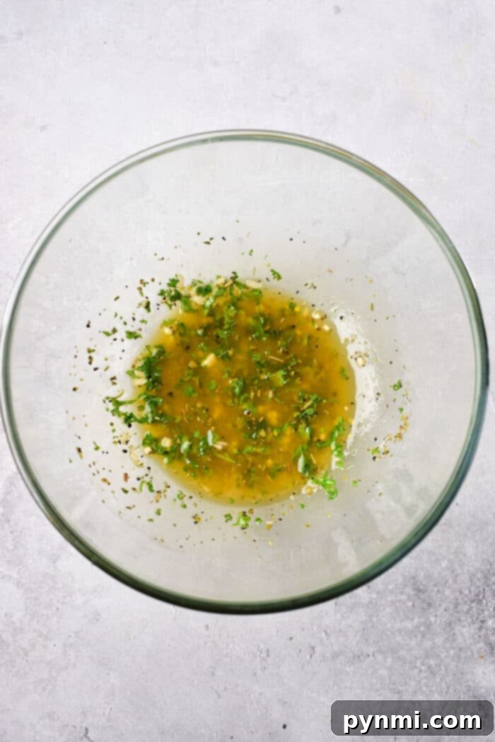 Vibrant Mediterranean Chicken Marinade 3 A close-up shot of a variety of fresh Mediterranean marinade ingredients, including herbs, lemon, and garlic, prepared for mixing in a bowl.