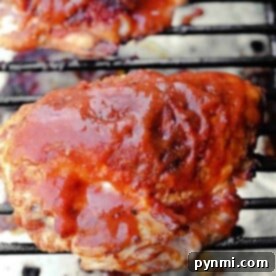 Smoked chicken breast covered in barbecue sauce is grilling on the barbecue grate.