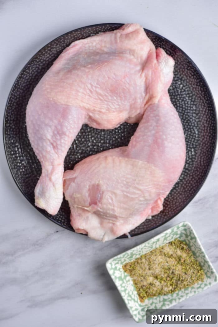 Juicy and Tender Chicken Leg Quarters 4 Raw chicken quarters resting on a black plate with spices, ready to be seasoned and cooked to perfection.