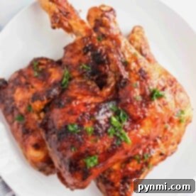 Grilled chicken quarters, expertly prepared, beautifully garnished with herbs on a white plate.