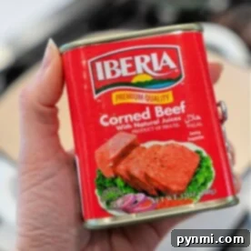 Hand holding a can of Iberia Corned Beef in natural juices, product of Brazil, with halal certification—perfect for your next canned corned beef recipe.