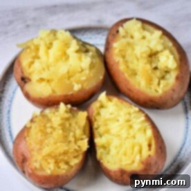 Four halved baked sweet potatoes with mashed insides sit on a plate, a tempting twist on comfort food that rivals even the most tender Instant Pot red potatoes.