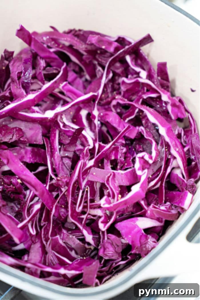 Sliced red cabbage, raw and vibrant, ready to be added to the Dutch oven, demonstrating the ideal 1/2-inch thickness.