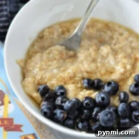 A bowl of oatmeal topped with blueberries sits enticingly next to a package of gluten-free oats, offering a perfect start to your day. Discover the delightful texture and taste that comes from knowing how to cook steel-cut oats just right.