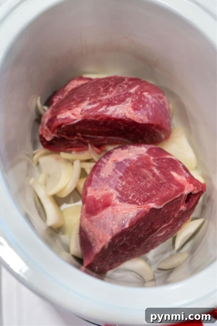 Mastering the Perfect Pork Picnic Roast 4 Two raw pork picnic roast rest in a slow cooker, surrounded by sliced onions.