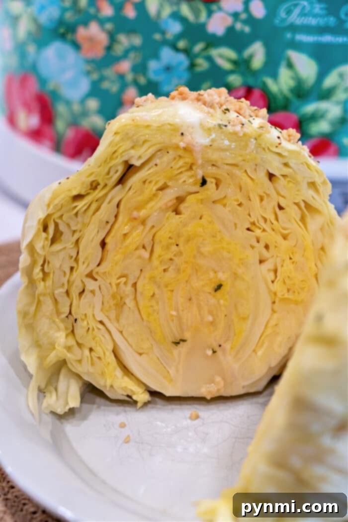 Perfect Slow Cooker Whole Cabbage 7 Close-up of a sliced cabbage on a plate, its layered texture and light yellow color beautifully contrasted against a colorful floral background, reminiscent of the tenderness achieved from cooking a whole head of cabbage in a slow cooker.