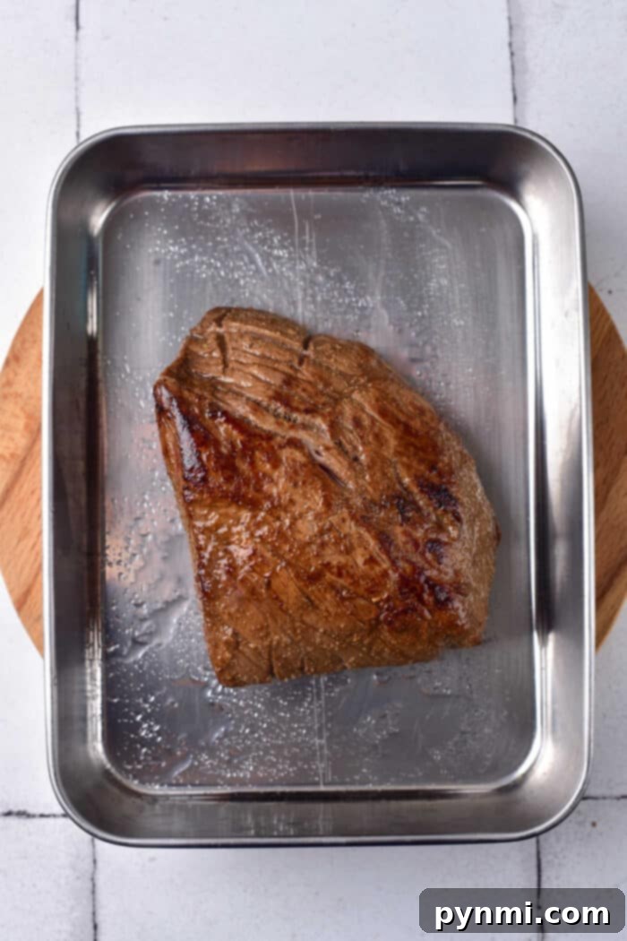 Perfectly cooked London Broil, sliced and ready to serve, showing a juicy medium-rare center