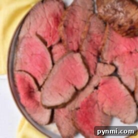 Sliced roast beef, reminiscent of learning how to cook a London Broil in the oven, is artfully arranged on a plate atop a yellow cloth background.