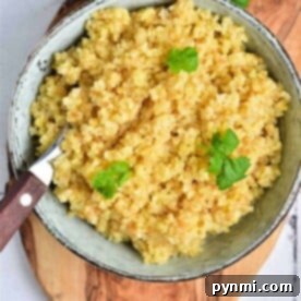 A bowl of cooked bulgur, garnished with cilantro and artfully served on a wooden board with a fork beside it, showcases the simple elegance of this dish.