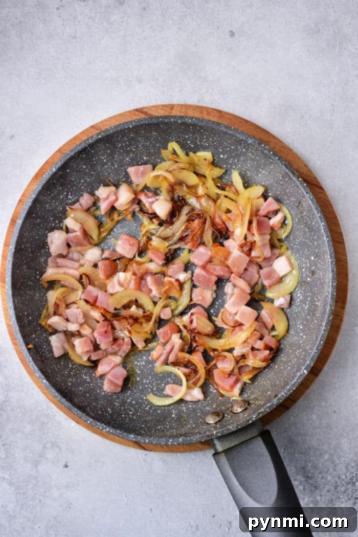Mastering Deer Liver Cooking 5 A frying pan with diced venison, sautéed onions, and tender slices of deer liver rests on a light gray background.
