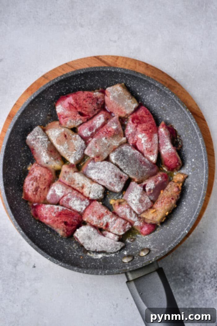 A plate of pan-fried pork liver garnished with fresh parsley and sesame seeds