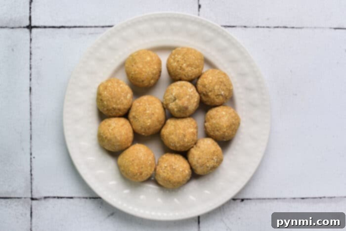 A beautiful display of golden-brown matzo balls on a white, textured plate, ready to be added to a flavorful soup.