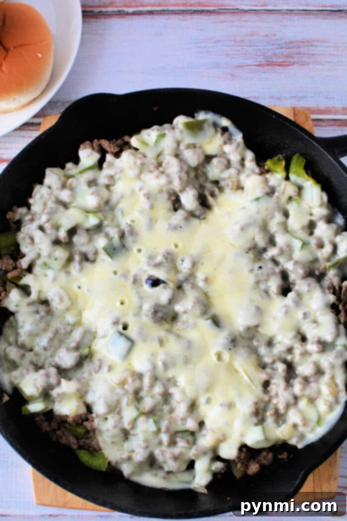 Philly Cheesesteak Sloppy Joes 5 Ground Beef Philly Cheesesteak Sloppy Joes in a slow cooker, topped with melted provolone cheese, ready to be served.