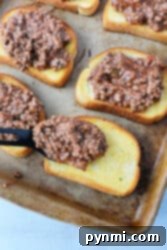 Texas toast sloppy joes come to life as a ground beef mixture rests atop hearty slices of bread on a baking tray.