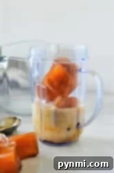 Ice cubes, milk, and a hint of frozen coffee sit in a blender cup on the kitchen counter.