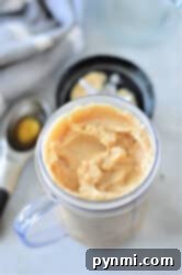 Frozen coffee in a clear container with a black lid, accompanied by an ice cream scoop nearby.