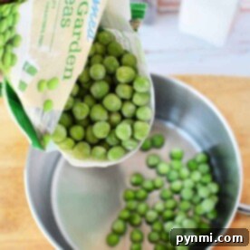 A bag of frozen peas cascades into a saucepan, landing softly on the wooden surface.