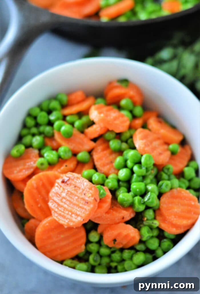 Serving of perfectly cooked frozen peas and carrots, garnished and ready to eat