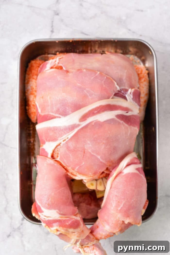 Gourmet Bacon-Wrapped Stuffed Chicken 4 Close up of a whole chicken seasoned and wrapped in bacon strips