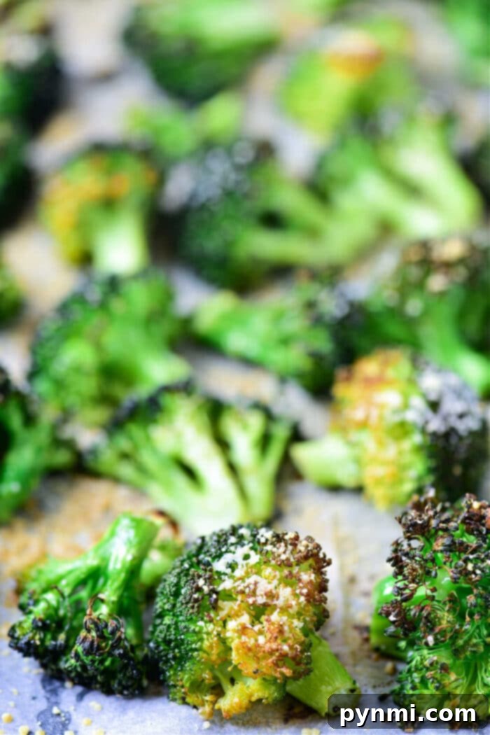 A close-up of beautifully baked frozen broccoli florets on a baking sheet lined with parchment paper, showcasing their golden-brown edges and tender appearance.