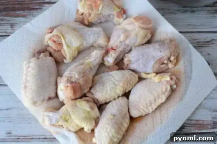 Several raw chicken wings placed on a paper towel, to dry.