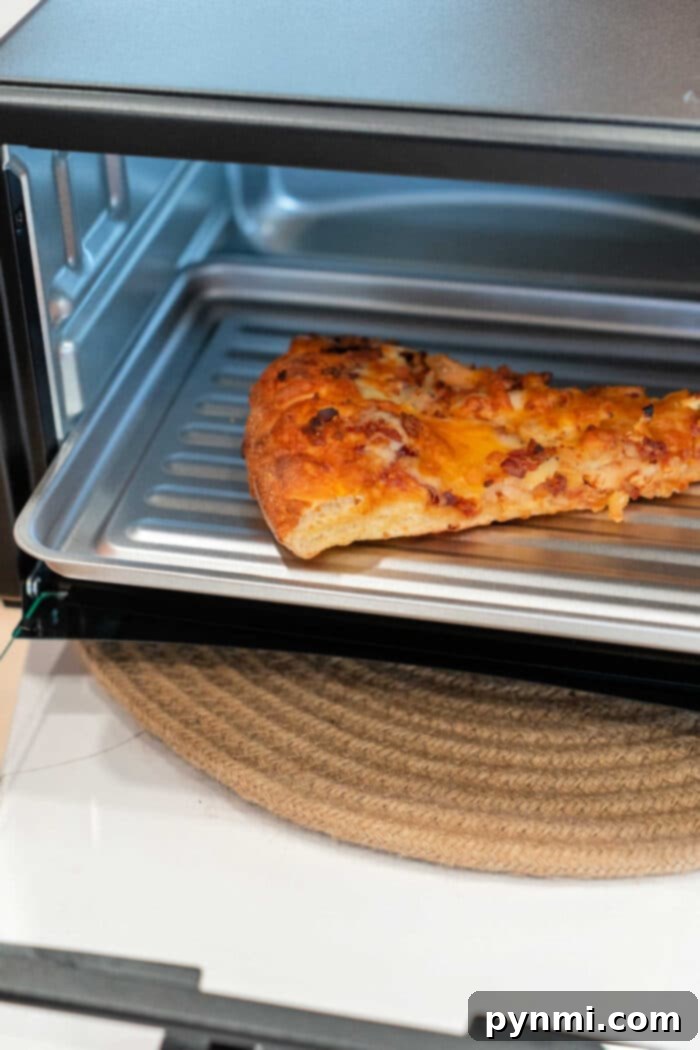 Crispy Pizza Revival: Toaster Oven Method 3 Crispy pizza slice heating in a toaster oven
