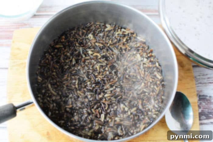 Unlock Perfect Rice Timing 3 A rustic pot of wild rice cooking on a wooden cutting board, steam gracefully rising, with a stainless steel bowl and spoon nearby. This image perfectly captures the essence of preparing wholesome grains.