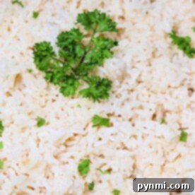 A close-up of cooked rice, garnished with sprigs of fresh parsley, inviting the question: how long does rice take to cook to perfection?