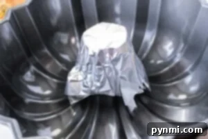 A bundt pan with a small metal cup covered in aluminum foil placed upside down at the center is perfect for creative baking. The pan, designed with a non-stick surface and ribbed pattern, can also be an inventive way to measure how long to cook a whole chicken evenly.