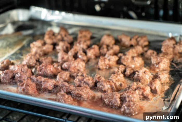 Perfect Ground Beef Every Time: Your Cooking Guide 5 ground beef sizzle on a foil-lined baking sheet in the oven, turning golden brown. It's crucial to know how long to cook ground beef for perfect doneness and flavor, ensuring a juicy delight every time.