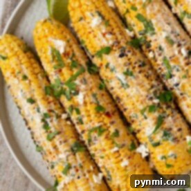 Grilled elote corn on a plate, topped with crumbled cheese, cilantro, and a lime wedge on the side. For a quicker option, consider microwaving your corn first to ensure its perfectly tender before grilling.