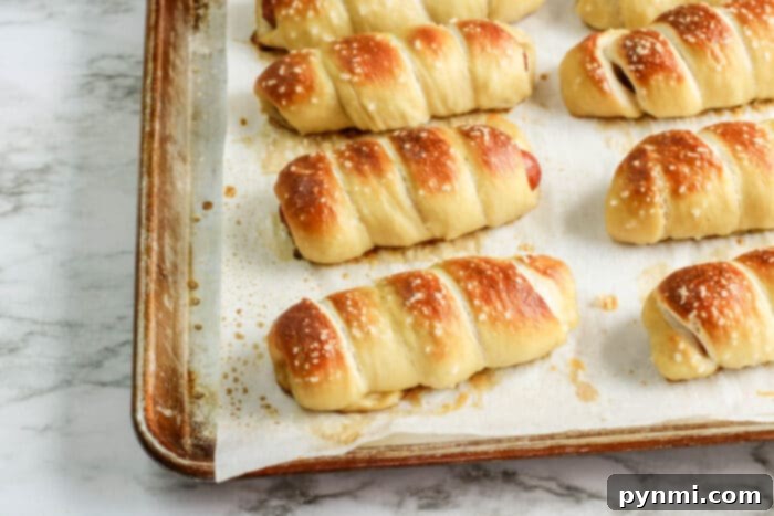 Savory Sausage Puffs 4 pretzel pigs in a blanket stacked on a plate with dipping sauce