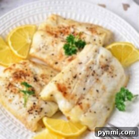Three pieces of baked fish, cooked just right, with lemon slices and a sprinkle of parsley on a white plate. Perfectly timed like knowing how long to cook cod for that tender, flaky texture everyone loves.