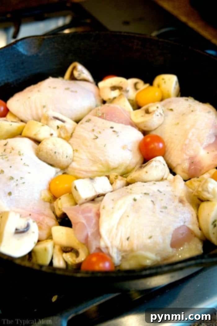 Bone-in chicken thighs baking in the oven with fresh herbs for a flavorful meal.