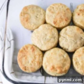 Biscuits, crafted with the classic Hardees Biscuits Recipe, are neatly arranged in a baking dish, resting on a white towel adorned with brown grid lines.