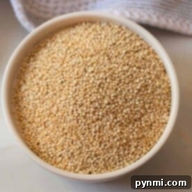 Unlock Fluffy Quinoa: The Secret to Perfect Grain 7 A bowl filled with uncooked quinoa rests on a countertop, accompanied by a textured cloth, all poised to reveal just how long to cook quinoa for that perfect fluffy texture.