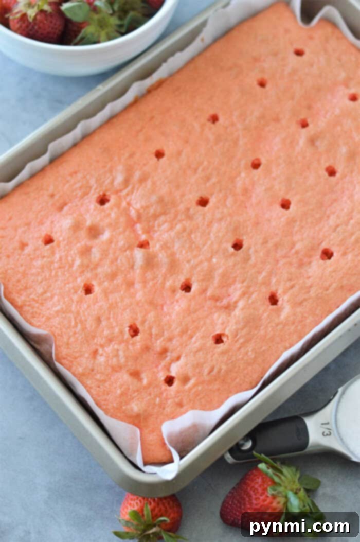 A slice of vibrant strawberry poke cake, showcasing the infused strawberry sauce and light whipped topping with fresh strawberry slices, on a white plate.