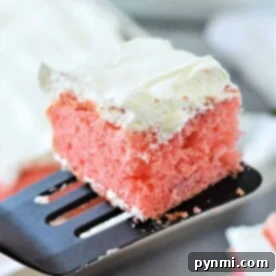 Slice of pink cake made from cake mix with strawberries, adorned with white frosting, sitting elegantly on a spatula, with a fresh strawberry nearby.